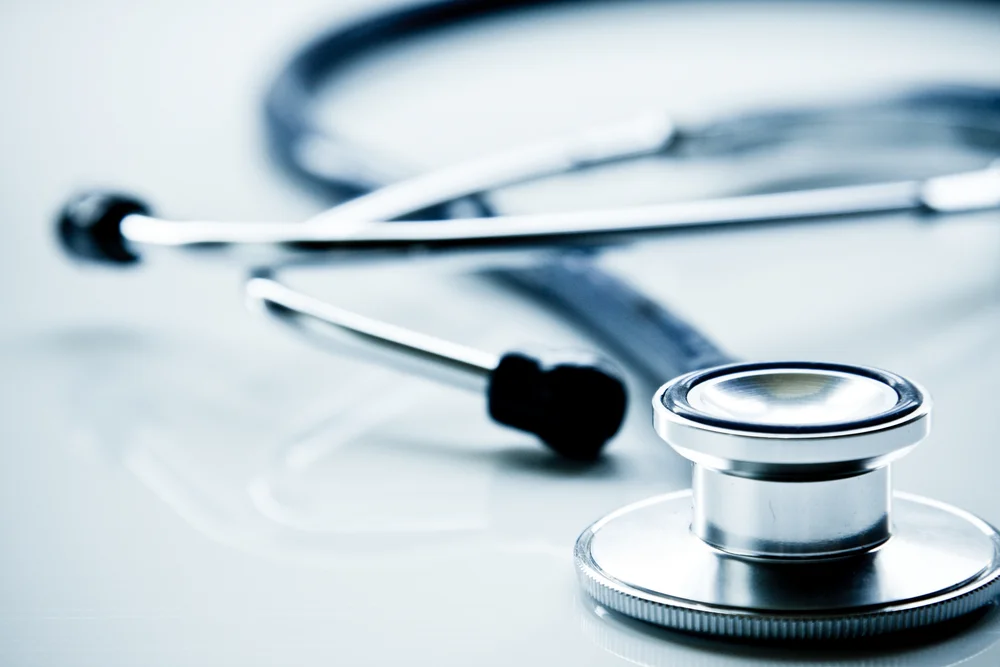 Close-up of a stethoscope resting on a reflective surface, cool blue tones, clinical mood